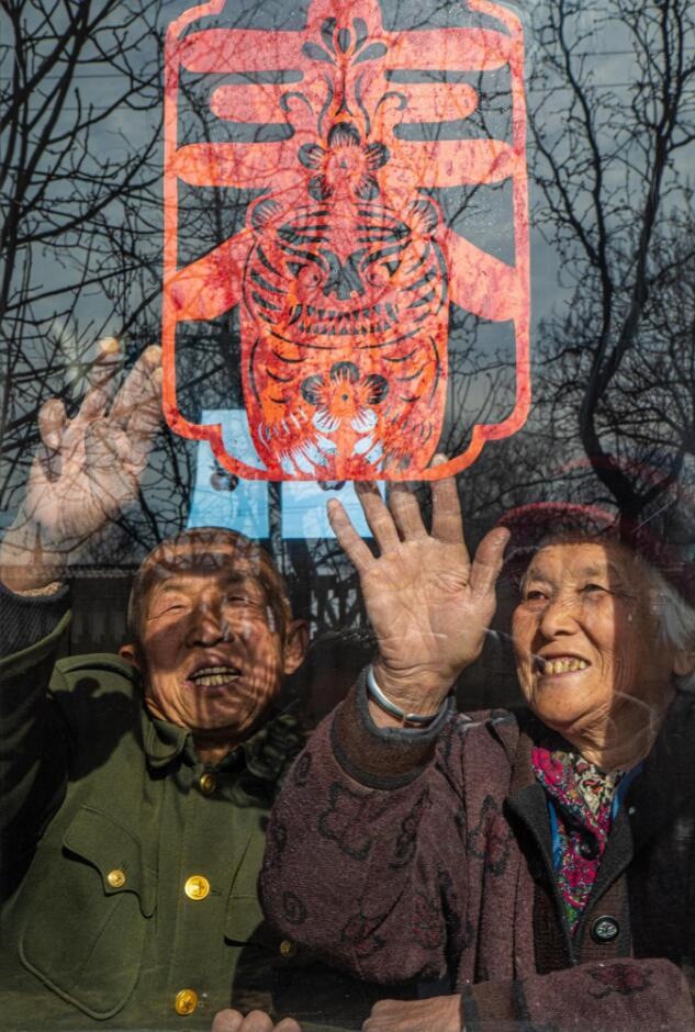 臘月里，霍州市師莊鄉(xiāng)馮南垣村村民師榮光(左)在災(zāi)后重建的新家里貼窗花。(霍州市委宣傳部供圖)