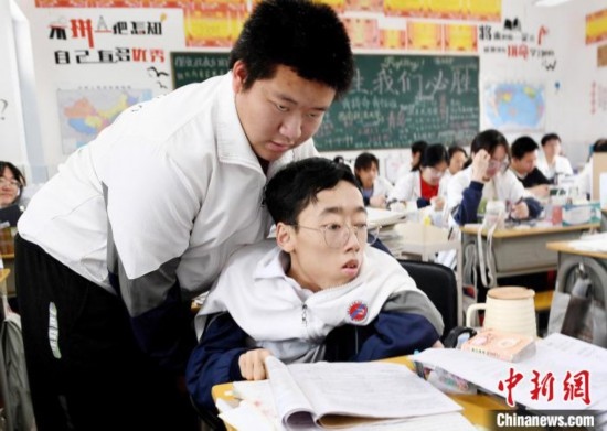 朱金祥(左)把鐘華強放到課堂座位上后，都要把他擺正好，確認安全后才回到自己的座位上。 卓忠偉 攝