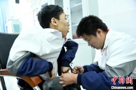 江西省南康中學(xué)北校區(qū)的高三學(xué)生朱金祥(右)正在給鐘華強(左)系好鞋帶。 卓忠偉 攝