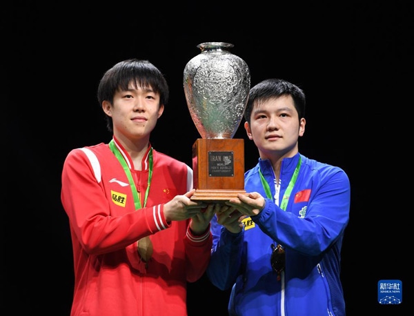 5月27日，樊振東（右）/王楚欽在頒獎(jiǎng)儀式上高舉獎(jiǎng)杯慶祝。當(dāng)日，在南非德班進(jìn)行的2023年世界乒乓球錦標(biāo)賽男雙決賽中，中國(guó)組合樊振東/王楚欽以3比0戰(zhàn)勝韓國(guó)組合張禹珍/林鐘勛，奪得冠軍。新華社記者 李亞輝攝