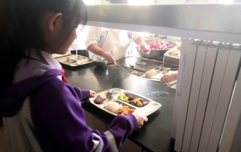 伊金霍洛旗第一小學(xué)學(xué)生正在打飯，今天的飯菜是三菜一湯外加水果，學(xué)生可以多次盛取，吃飽為止。人民網(wǎng)記者 孫博洋攝