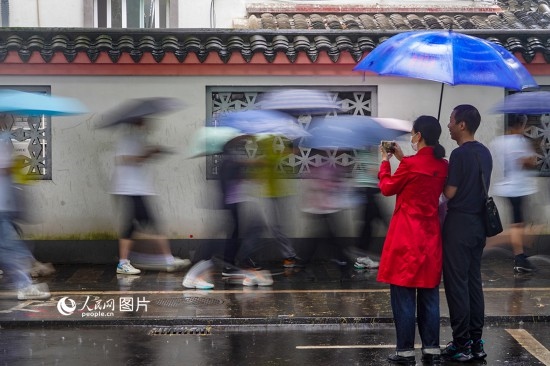 6月7日，在浙江省2023年普通高校招生考試鎮(zhèn)海中學(xué)考點(diǎn)，家長(zhǎng)冒雨目送子女進(jìn)入考場(chǎng)。人民網(wǎng) 章勇濤攝