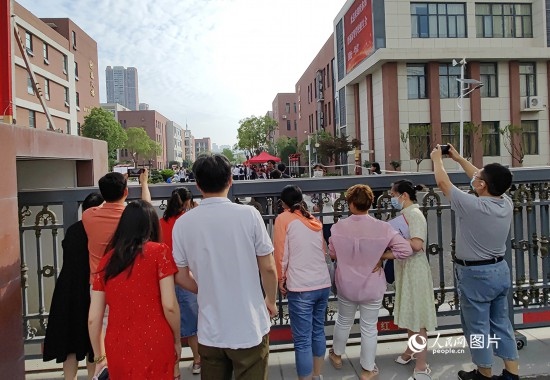 6月7日，武漢市第三中學(xué)考點(diǎn)，考生進(jìn)場(chǎng)后，家長(zhǎng)在柵欄外用手機(jī)拍攝自己的孩子。人民網(wǎng)記者 郭婷婷攝