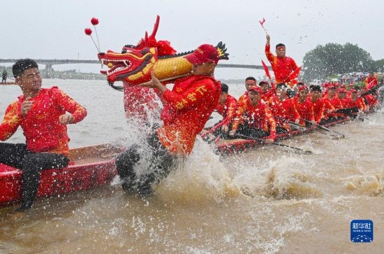 6月22日，在湖南省岳陽市湘陰縣湘江臨資口水域，參加龍舟賽的隊員接“龍頭”下水。