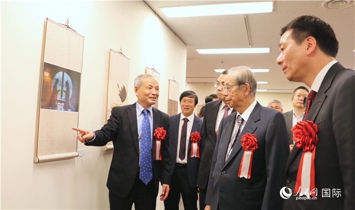 “湖州印象”攝影展主創(chuàng)、世界華人攝影協(xié)會副會長馮學(xué)敏向吳江浩大使、福田康夫前首相等嘉賓介紹展出作品。（人民網(wǎng) 許可攝）