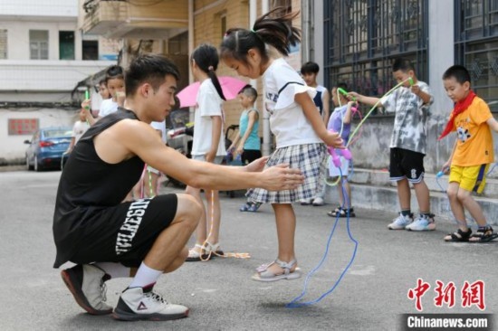 圖為大學(xué)生志愿者在教孩子們學(xué)跳繩。廖光福 攝