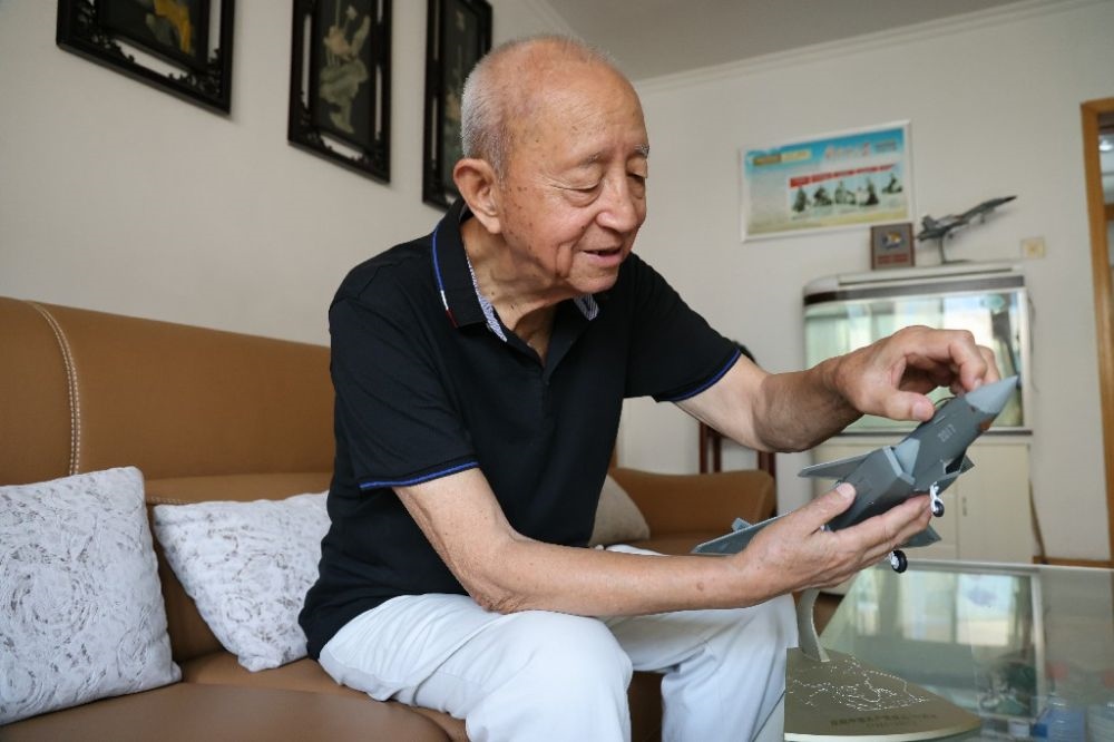 ↑2023年7月24日，新中國第一代飛行員陶偉在家中擦拭殲-20飛機(jī)模型。新華社發(fā)（張瑞 攝）
