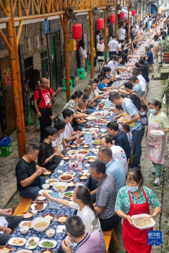 7月29日，在重慶市綦江區(qū)安穩(wěn)鎮(zhèn)，人們在“苗家伏羊節(jié)”上吃長桌宴。新華社記者 唐奕 攝