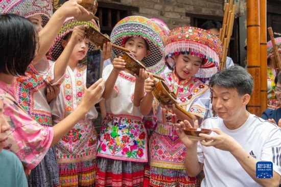7月29日，在重慶市綦江區(qū)安穩(wěn)鎮(zhèn)，當(dāng)?shù)鼐用裨凇懊缂曳蚬?jié)”上用傳統(tǒng)習(xí)俗向游客表達(dá)祝福。新華社記者 唐奕 攝