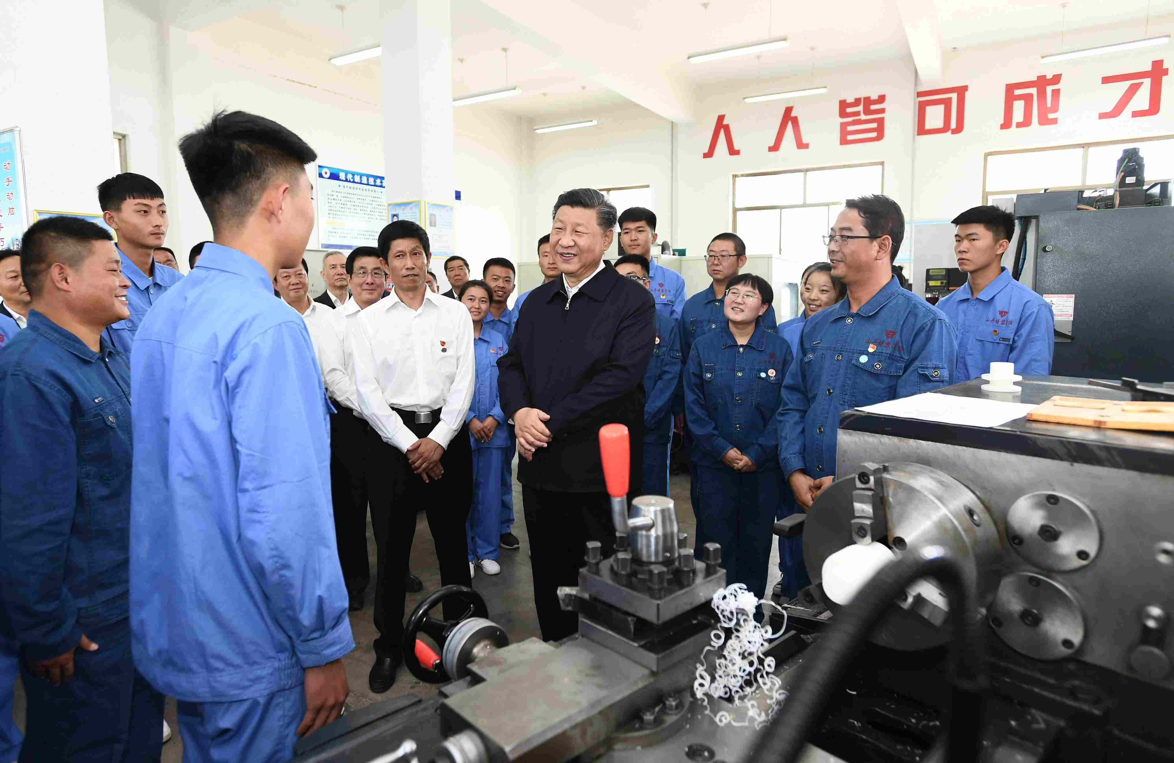 2019年8月20日，習近平在甘肅省張掖市山丹培黎學?，F(xiàn)代制造技術(shù)實訓室，觀看職業(yè)技能實訓，同師生親切交流。