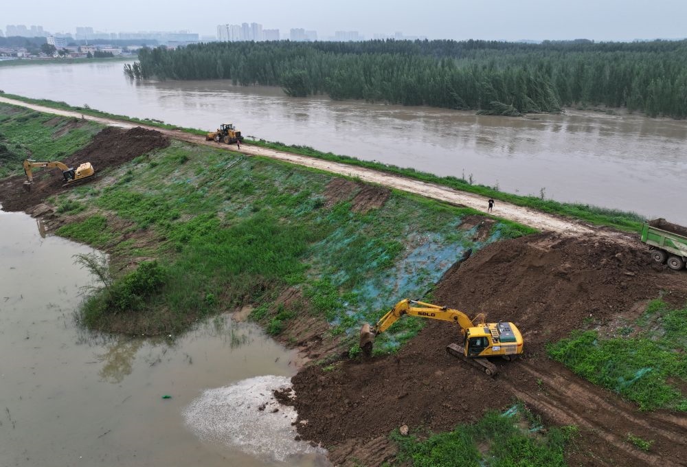 工人操作機(jī)械在白溝河左堤白溝新城高橋村段進(jìn)行除險(xiǎn)加固作業(yè)（8月4日攝，無(wú)人機(jī)照片）。新華社記者 朱旭東 攝