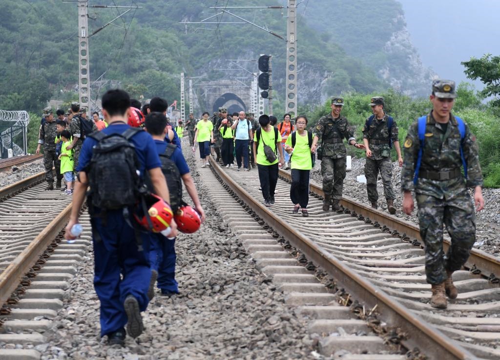 8月2日，部分滯留在北京市門頭溝山區(qū)受困列車的旅客，在救援人員幫助下前往轉(zhuǎn)運(yùn)客車。新華社記者張晨霖 攝