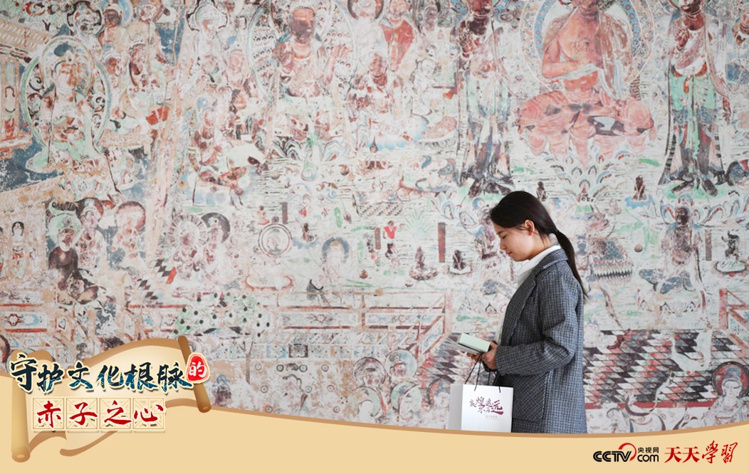 2023年4月25日，敦煌研究院文物數(shù)字化保護(hù)團(tuán)隊創(chuàng)意營銷人員廖雪婷從一幅高保真復(fù)制壁畫前走過。