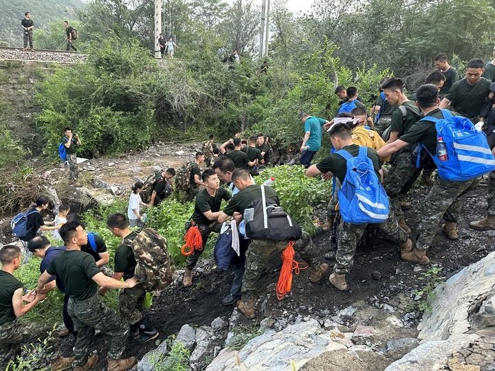 8月2日，Z180次受困列車的旅客在武警北京總隊(duì)機(jī)動(dòng)第三支隊(duì)官兵的幫助下徒步前往轉(zhuǎn)運(yùn)客車（手機(jī)照片）。新華社記者 王艷剛 攝