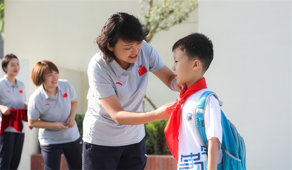 8月30日，雄安史家胡同小學(xué)學(xué)生體驗(yàn)學(xué)校生活。老師為學(xué)生佩戴?；?。