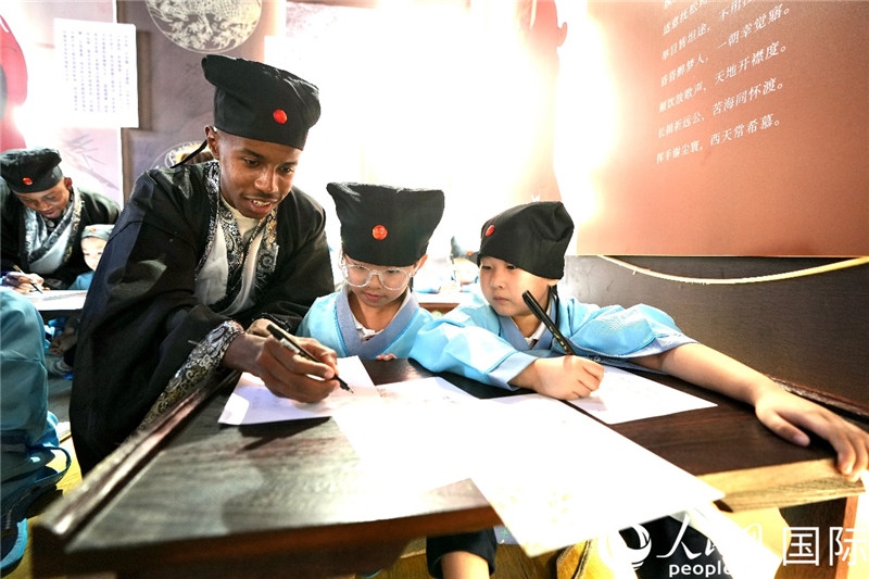 圖為選手與同學們一起寫書法。人民網(wǎng) 盧鵬宇攝