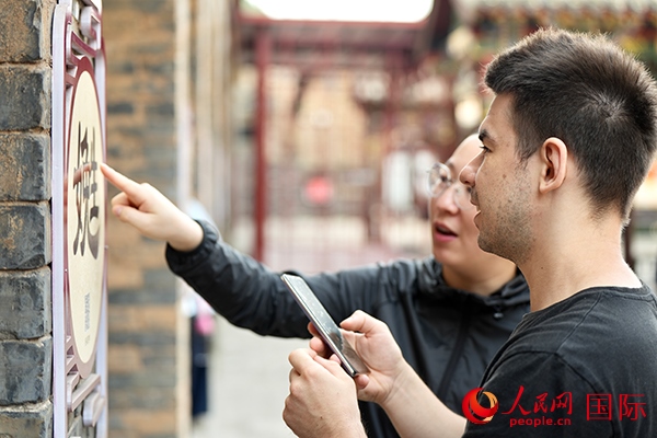 選手安德烈（俄羅斯）在老師指導(dǎo)下學(xué)習(xí)墻壁上張貼的生僻字。人民網(wǎng) 盧鵬宇攝