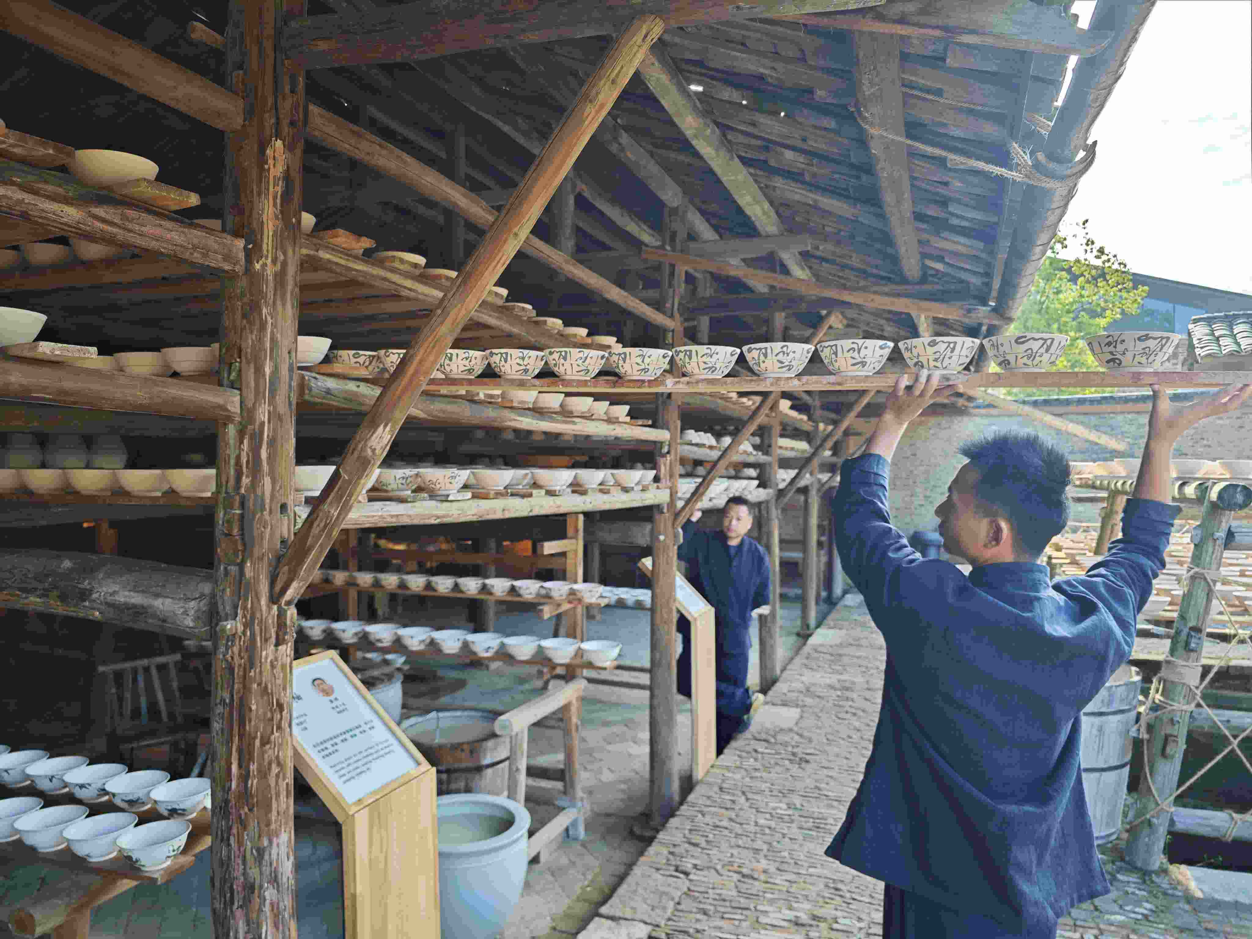 △陶陽里歷史文化街區(qū)里，工匠將陶瓷工藝品放到架上晾干。（總臺(tái)央視記者彭漢明拍攝）