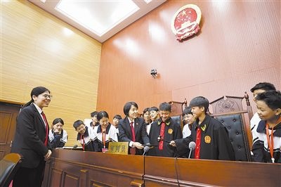 圖③：同學(xué)們穿法袍、敲法槌，爭做“小法官”。