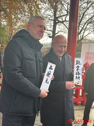 柏林市長韋格納（右）、動物園監(jiān)事會主席布魯克曼（左）手持中國文化中心工作人員現(xiàn)場手書的中文名字。人民網(wǎng)記者 徐馨攝