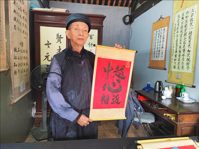 越南首都河內文廟內，阮明珠展示“中越心相近”書法作品。