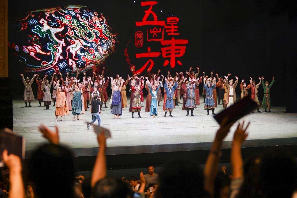 2023年7月31日，新疆和田地區(qū)新玉歌舞團(tuán)在烏魯木齊京劇院演出舞劇《五星出東方》后和觀眾互相揮手致意。這場(chǎng)演出是第六屆中國(guó)新疆國(guó)際民族舞蹈節(jié)的參演劇目之一，曾榮獲國(guó)家“文華獎(jiǎng)”等。新華社記者 郝昭 攝