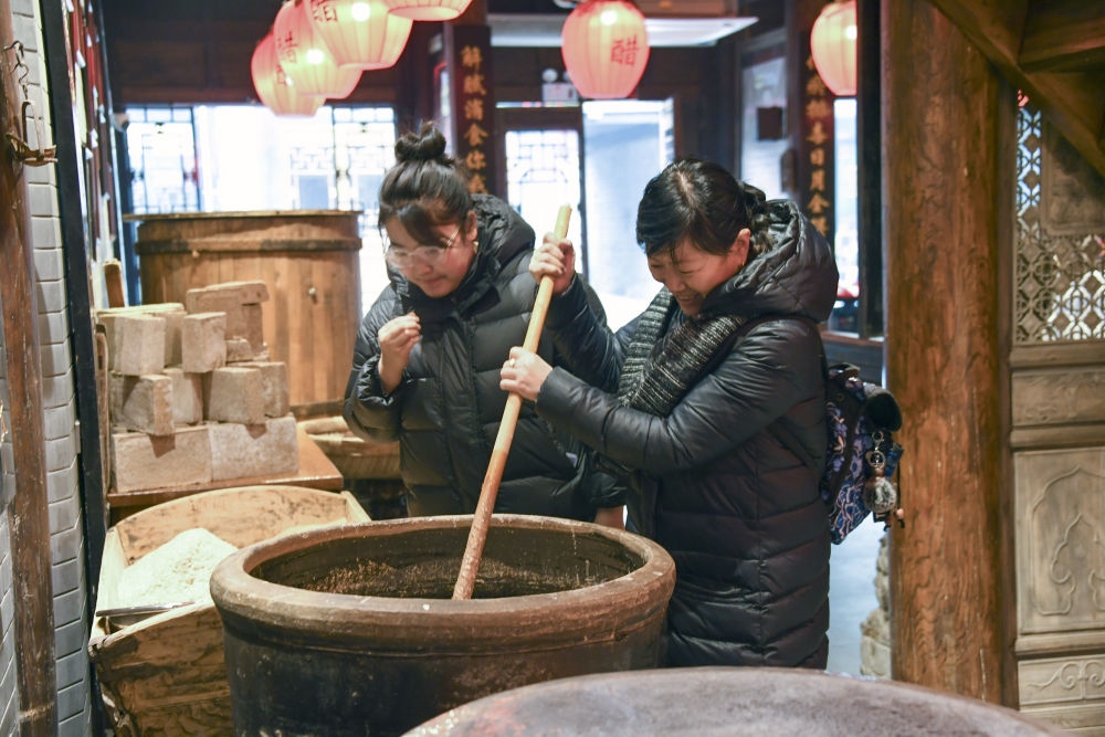 游客在平遙古城東湖老醋坊內(nèi)體驗(yàn)陳醋發(fā)酵打耙（2022年1月28日攝）。新華社發(fā)（梁生仁攝）