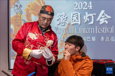 1月28日，在上海豫園舉行的民俗活動(dòng)上，美國(guó)馬斯卡廷中學(xué)學(xué)生在非遺傳承人的指導(dǎo)下吹糖偶。 新華社記者 王翔 攝