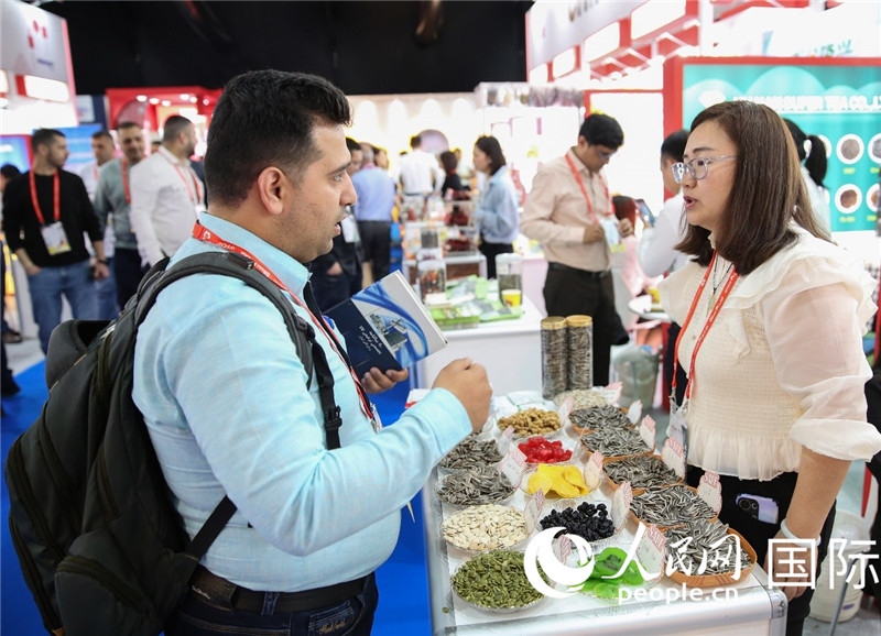 圖為一家中國干果參展企業(yè)代表與采購商洽談。人民網(wǎng) 塔里克·易卜拉欣攝