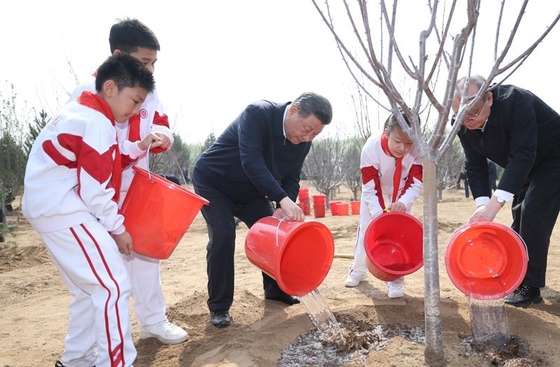 2024年4月3日，習近平總書記同少先隊員一起給剛栽下的樹苗澆水。