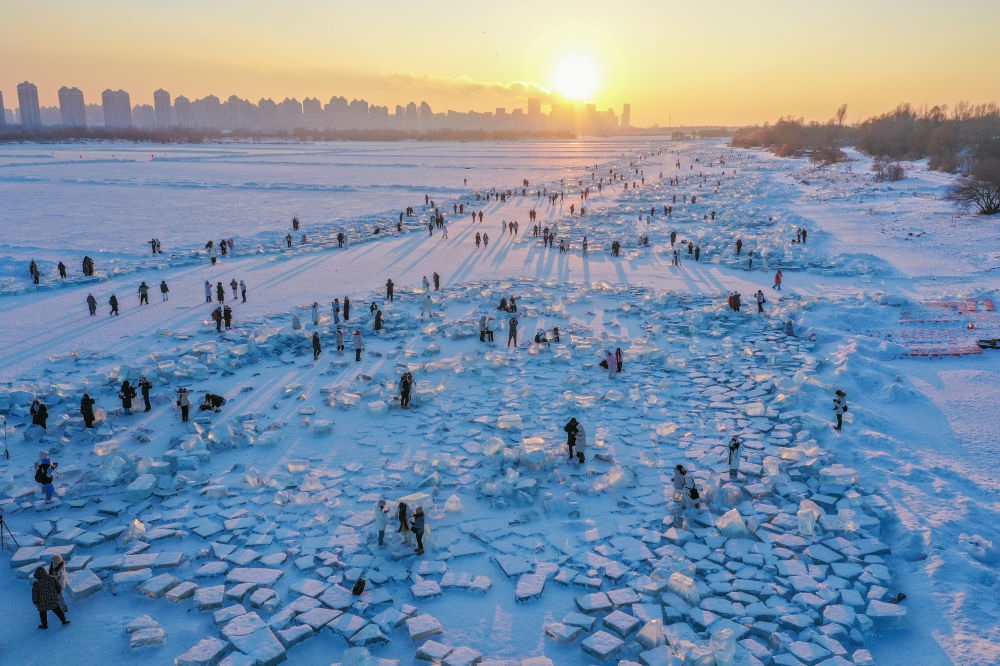 2024年1月7日，在封凍的松花江哈爾濱段，游客在日落時(shí)分的“鉆石海”游玩（無(wú)人機(jī)照片）。新華社記者 謝劍飛 攝