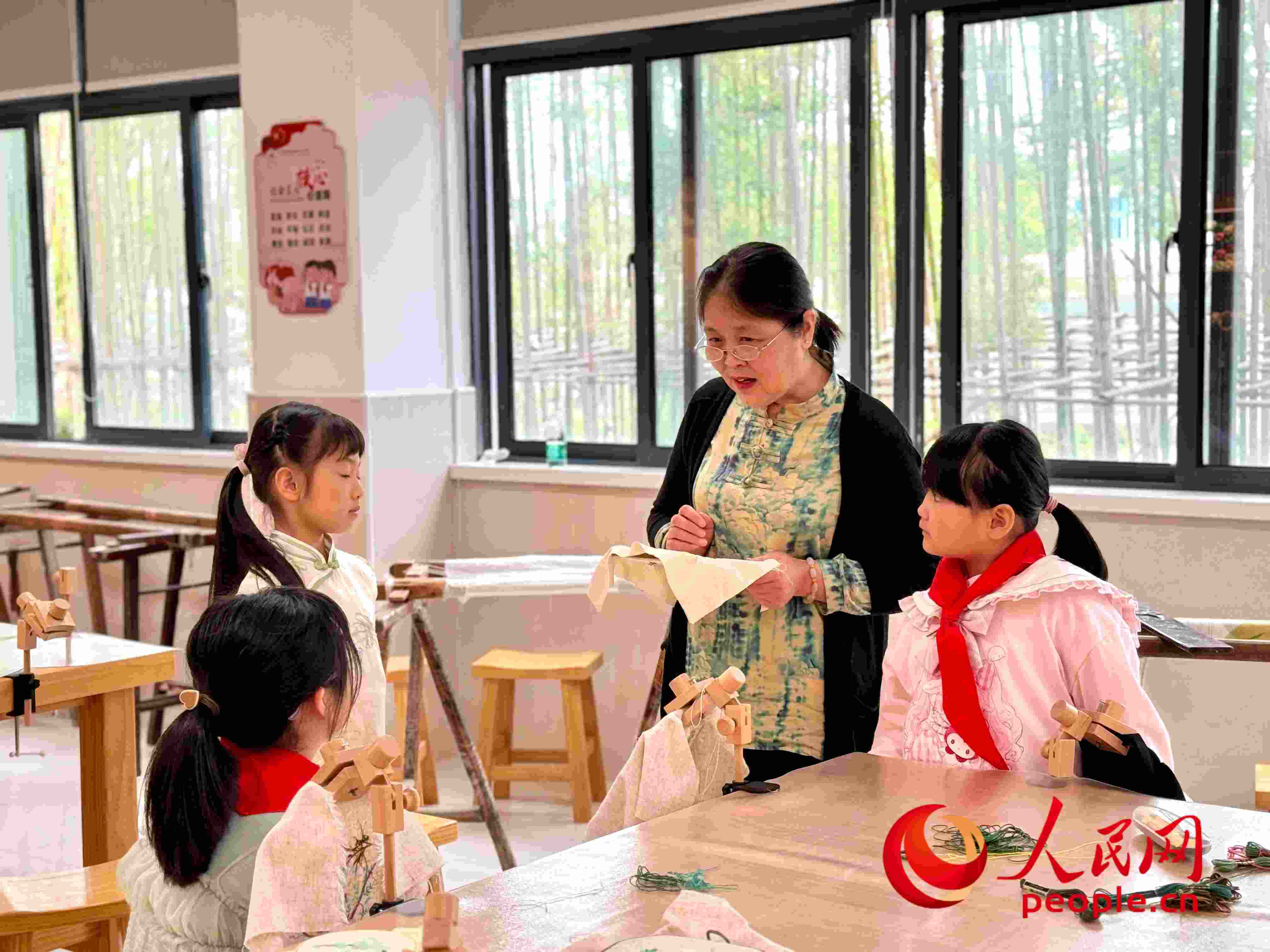 顧建珍（左三）在教孩子們刺繡知識。人民網(wǎng) 周靜圓攝