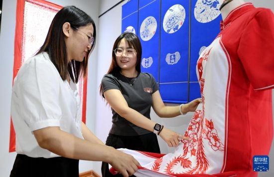 5月31日，在衡水市阜城縣一家剪紙工作室，游客在觀賞帶有剪紙元素的旗袍。