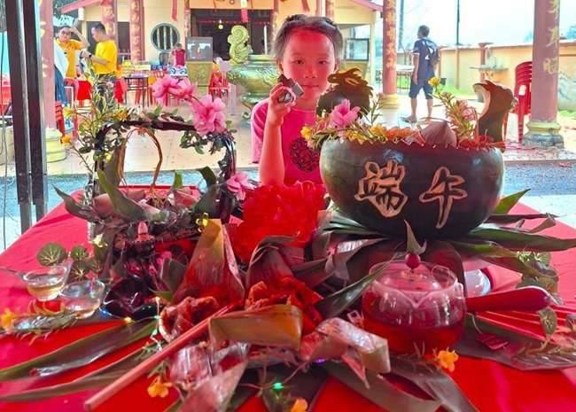 小朋友展示學(xué)裹粽子的成品照。組委會供圖