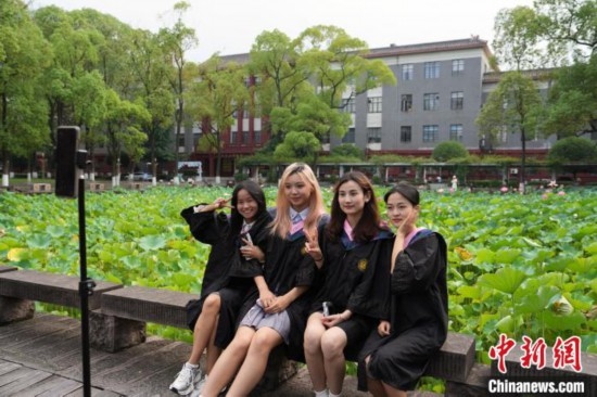 6月19日，時(shí)值一年畢業(yè)季，四川大學(xué)望江校區(qū)荷花池里的荷花盛開，成為了畢業(yè)生們的打卡圣地，吸引了眾多畢業(yè)生拍照留念。圖為畢業(yè)生在荷花池邊拍照留念。中新社記者 安源 攝