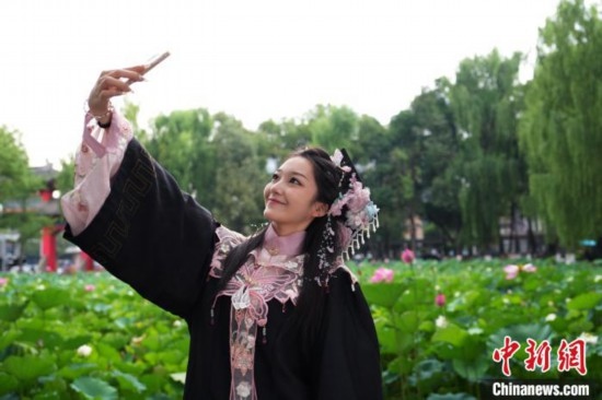 6月19日，時(shí)值一年畢業(yè)季，四川大學(xué)望江校區(qū)荷花池里的荷花盛開，成為了畢業(yè)生們的打卡圣地，吸引了眾多畢業(yè)生拍照留念。圖為畢業(yè)生在荷花池邊拍照留念。中新社記者 安源 攝