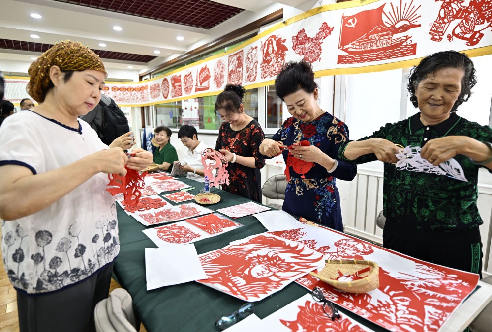 6月19日，長城花園社區(qū)居民在社區(qū)“才藝堂”制作剪紙。
