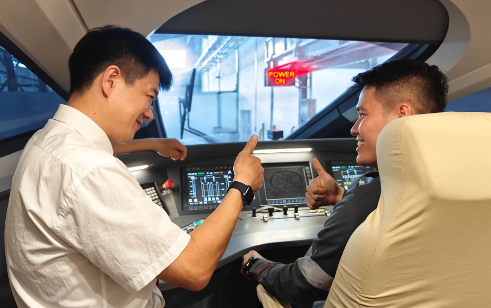 2023年8月25日，在印度尼西亞萬隆的雅萬高鐵德卡魯爾動車所內，中國師傅穆振（左）向印尼火車司機塞蒂亞萬講解動車組出庫前的上電作業(yè)。新華社記者 徐欽 攝