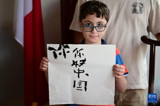 7月4日，在馬耳他桑塔露琪亞市的中國古典園林“靜園”，一名男孩展示他的書法作品。新華社發(fā)（喬納森·博格 攝）