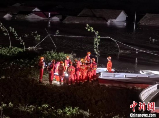  7月6日凌晨3時(shí)，在湖南岳陽(yáng)華容縣團(tuán)洲垸洞庭湖一線堤防，救援人員剛剛完成一次救援任務(wù)，遠(yuǎn)處是被淹的民房。中新社記者 白祖偕 攝