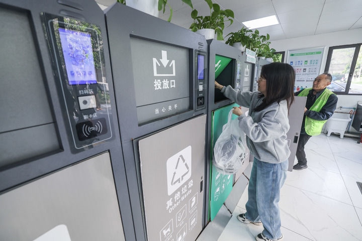 2024年4月10日，在浙江省湖州市吳興區(qū)飛英街道新華府小區(qū)內(nèi)，居民在垃圾分類智能系統(tǒng)的指導(dǎo)下進(jìn)行垃圾分類投放，居民的投放情況將實(shí)時(shí)匯總到智慧服務(wù)平臺(tái)，會(huì)有相應(yīng)的積分獎(jiǎng)勵(lì)。新華社記者 徐昱 攝