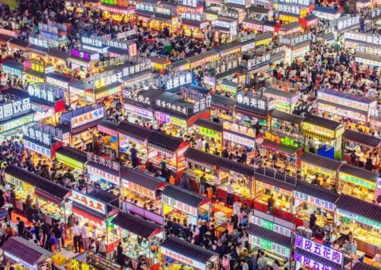 2024年4月21日，人們?cè)诤颖笔≌h小商品夜市品嘗美食（無(wú)人機(jī)照片）。新華社發(fā)（武志偉 攝）