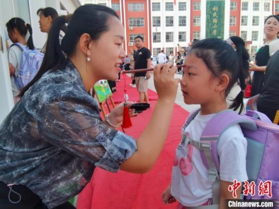 圖為衡水市利民路小學(xué)，老師為學(xué)生點朱砂痣，寓意開啟智慧。張松 攝