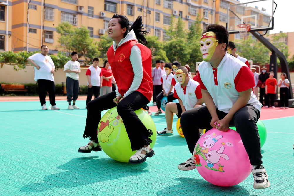 2024年5月17日，在山東省棗莊市市中區(qū)特殊教育中心，青年志愿者與智力障礙學(xué)生一起做游戲。新華社發(fā)（孫中喆攝）