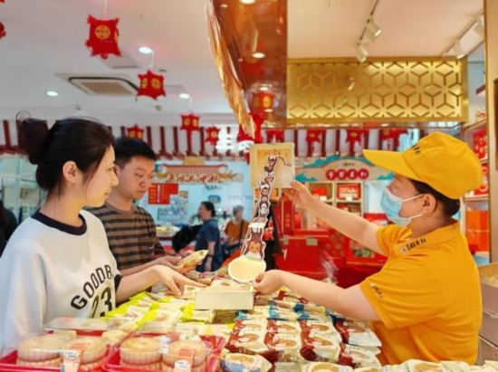 北京稻香村一家門(mén)店內(nèi)，售貨員向顧客展示新上市的月餅禮盒。（受訪者供圖）