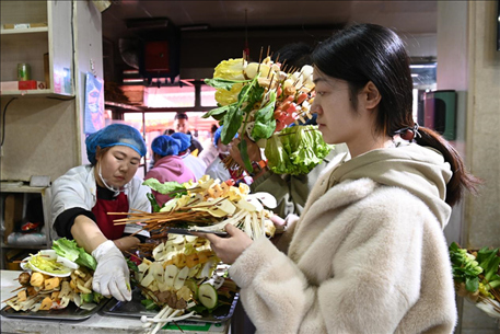 游客挑選好麻辣燙菜品后排隊等待加工。新華社記者 范培珅 攝