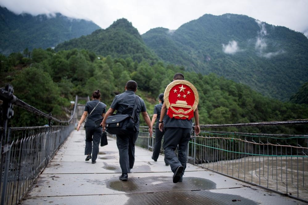 云南省怒江傈僳族自治州貢山縣人民法院法官鄧興背著國徽與同事們跨過怒江（2019年8月30日攝）。怒江高山峽谷眾多，交通不便，為方便群眾、更好地開展法律服務，背著國徽攀高山、過索橋、躲落石、鉆老林……成為鄧興法官的工作常態(tài)。新華社記者 江文耀 攝