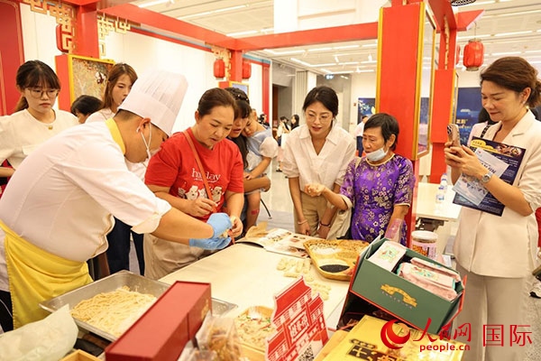 演出前，在天津桂發(fā)祥十八街麻花制作技藝非遺體驗(yàn)展臺(tái)前，泰國民眾體驗(yàn)天津麻花制作。人民網(wǎng)記者 楊一攝