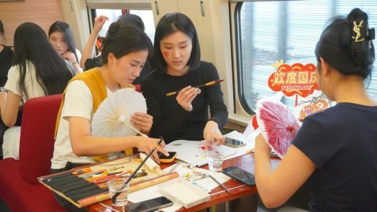 10月1日，旅客們在G1634次列車上給油紙傘作畫。新華社記者周義 攝