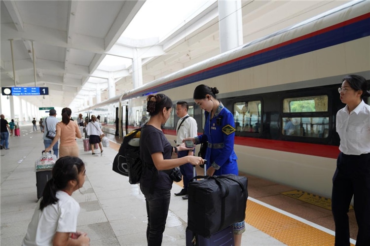 中老鐵路工作人員在站臺指引旅客進(jìn)站乘車。老中鐵路有限公司供圖